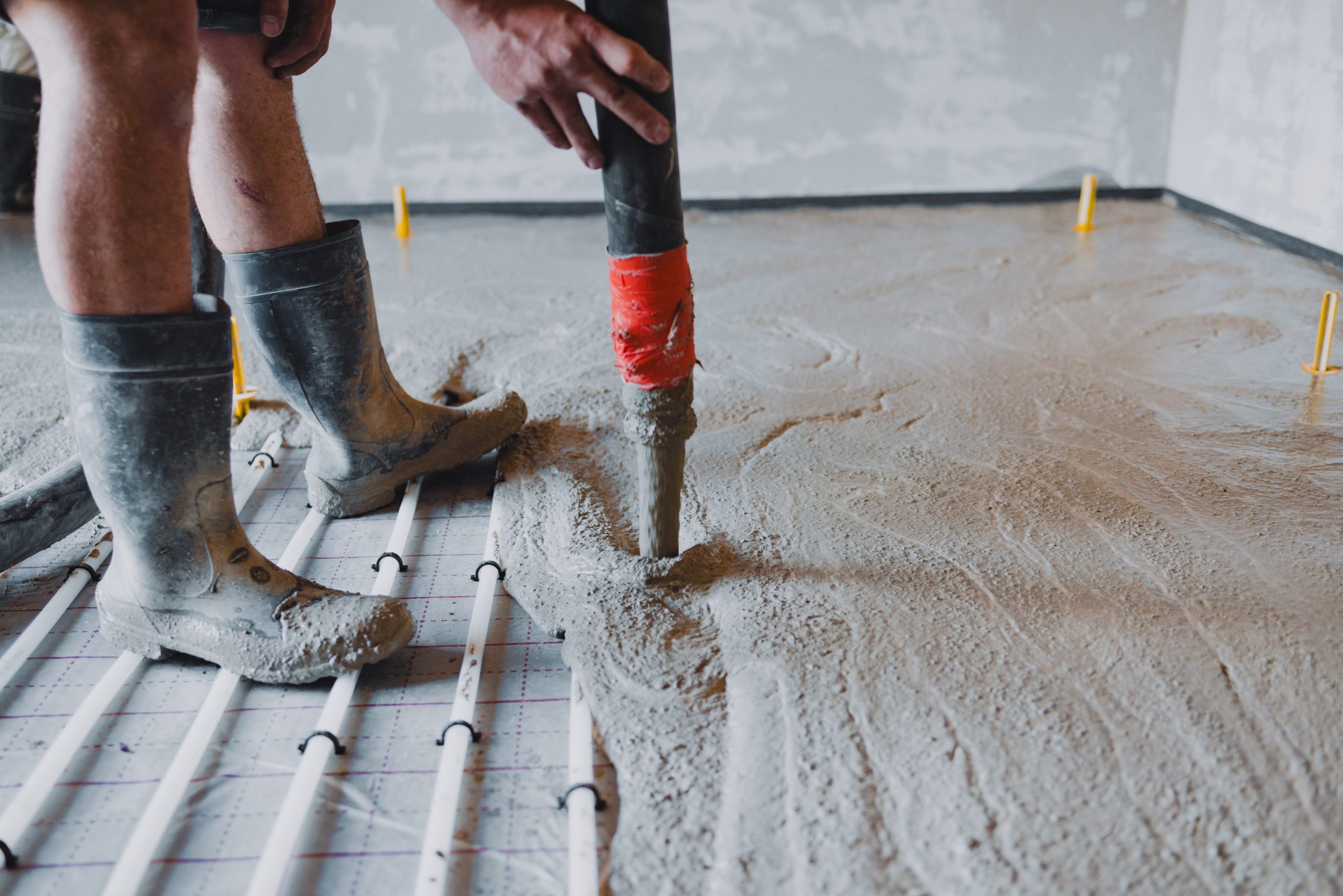 Construction worker pouring concrete on radiant floor heating system